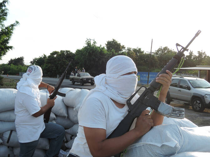 Members of a self-defense group guard a road near Nueva Italia, Mexico