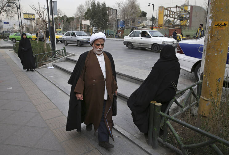 A clergyman make his way in a sidewalk in downtown Tehran, Iran, Sunday, Feb. 28, 2016. (AP Photo/Vahid Salemi)