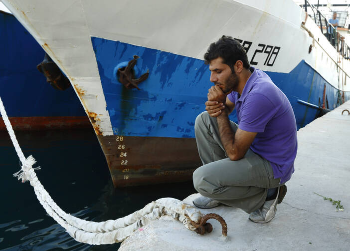 Syrian migrant attends commemorative service at harbor in Malta for immigrants who lost their lives at sea.