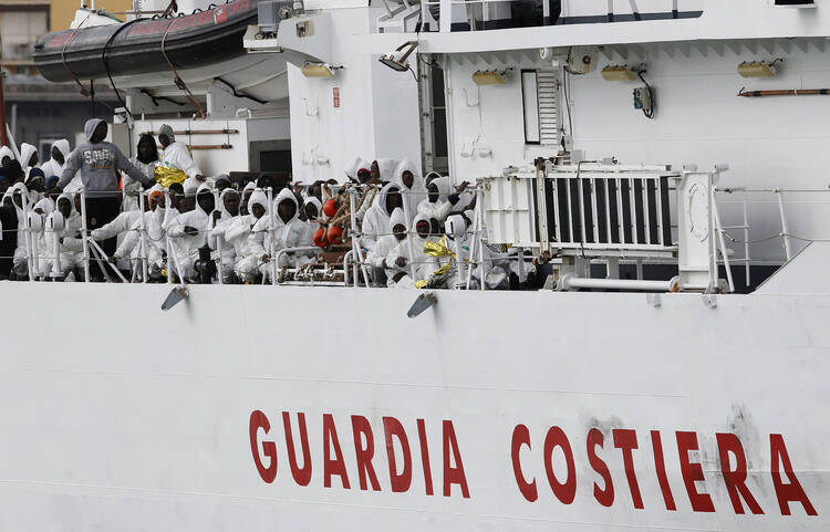 Migrants rescued from overcrowded boats near the Libyan coast stand on an Italian Coast Guard vessel on Feb. 14.