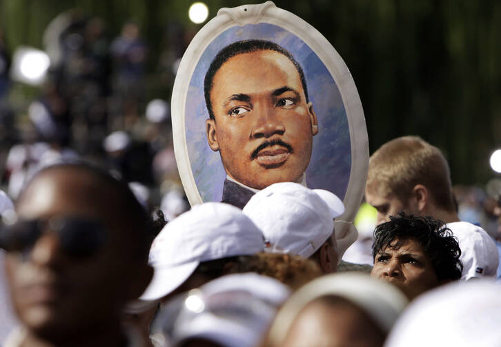 A woman holds a portrait of the Rev. Martin Luther King Jr. at the Oct. 16 dedication of a memorial to Rev. King in Washington. The memorial commemorates the life and work of the late civil rights leader. (CNS photo/Yuri Gripas, Reuters)