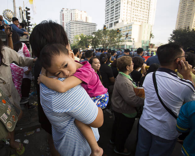 Mother holds sick child while waiting for pope in Manila, Philippines, Jan. 19 (CNS photo/Tyler Orsburn).