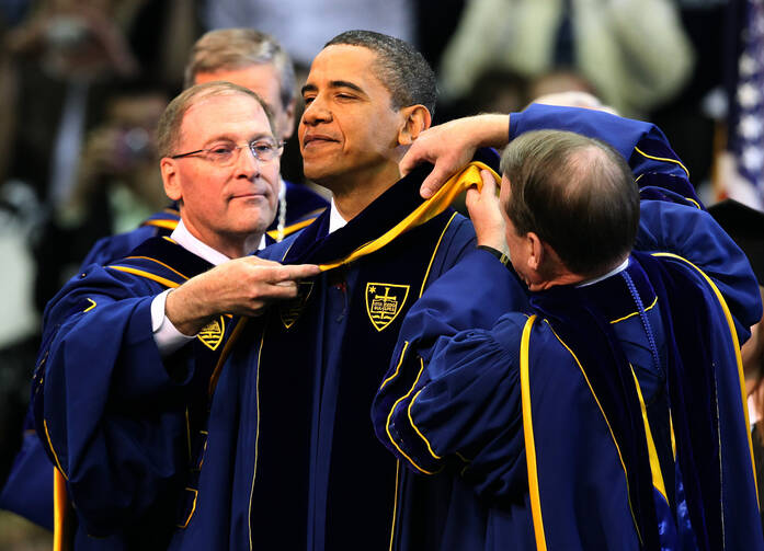 The chairman of the University of Notre Dame's board of trustees, Richard C. Notebart, and university registrar Harold L. Pace present U.S. President Barack Obama with an academic stole signifying the honorary degree he received during the commencement c eremony at the university in Notre Dame, Ind., in late May. (CNS photo/Christopher Smith)