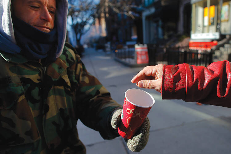 FOR YOUR SERVICE. A passerby gives some money to Chris, a homeless veteran of the United States’ wars in Iraq and Afghanistan, on Newbury Street in Boston, Mass.