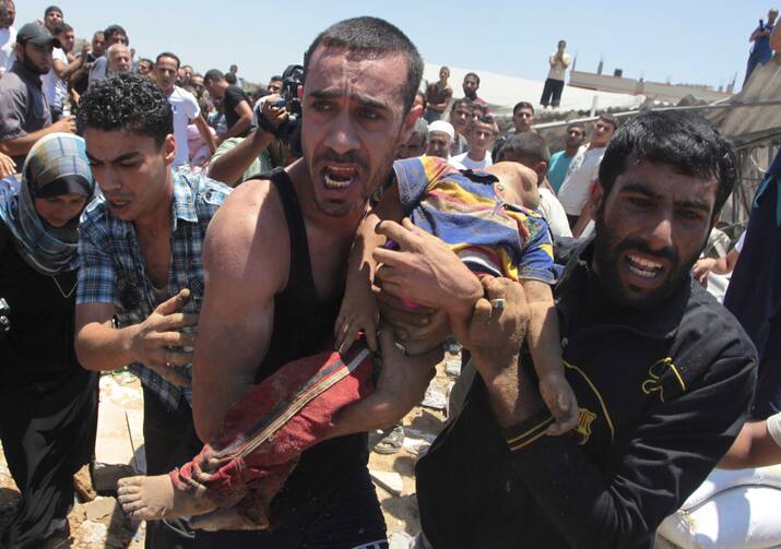 People carry the body of a Palestinian boy whom hospital officials said was killed in an Israeli airstrike on his family's house in Gaza City, July 9 (CNS photo/Ashraf Amrah, Reuters).