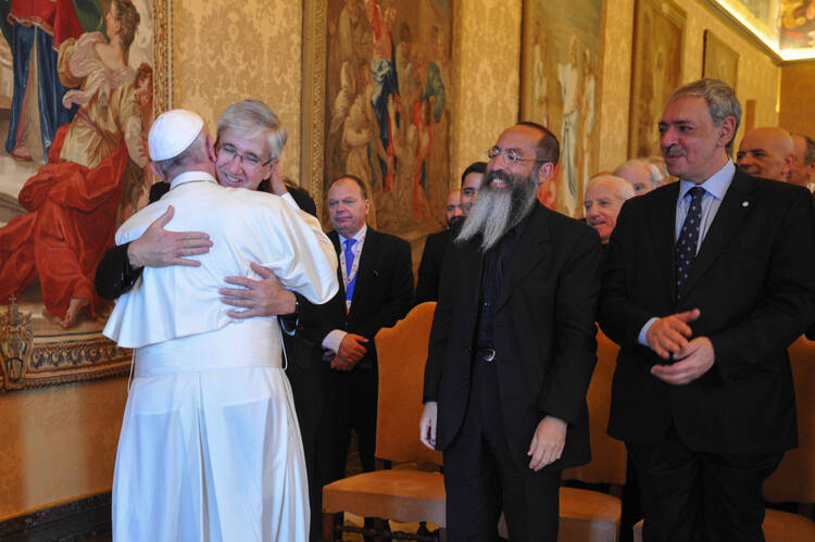 Pope embraces Father Guillermo Marco (his former press officer), as Rabbi Daniel Goldman and Islamic leader Omar Abboud look on.