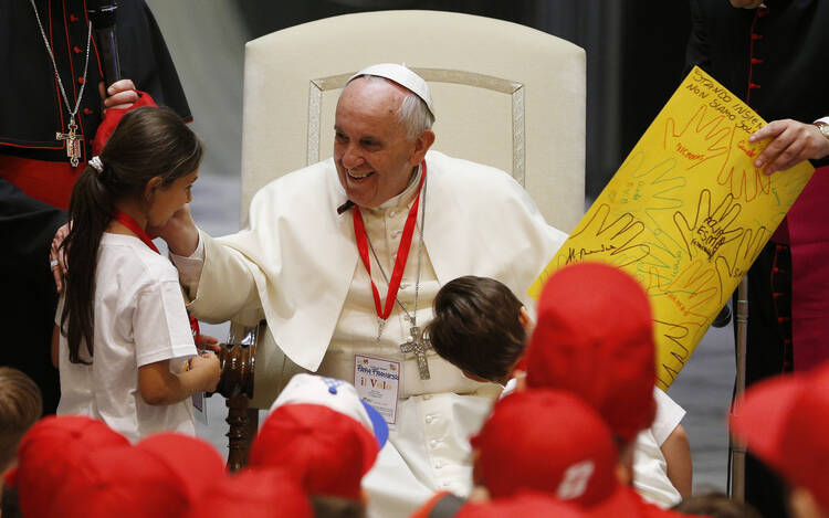 Pope Francis greets a girl after accepting a gift from her during a meeting with children of Italian prisoners in Paul VI hall at the Vatican May 30. (CNS photo/Paul Haring)