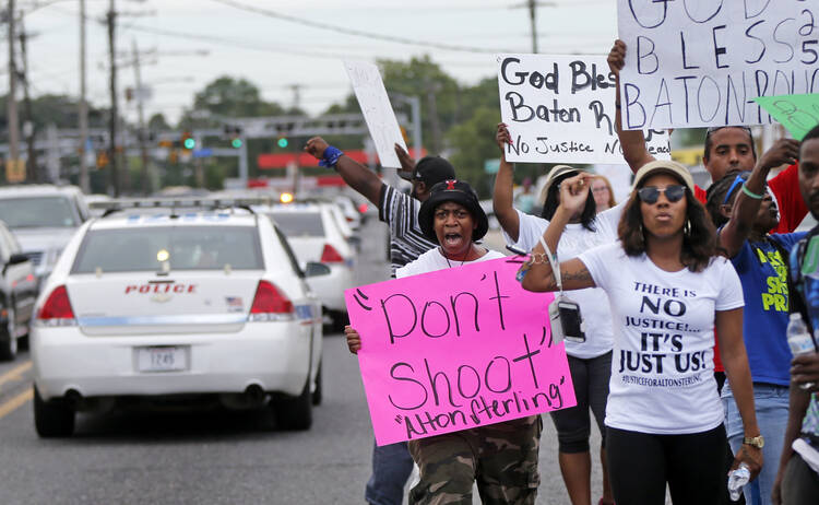 Police cars pass demonstrators on July 6 in Baton Rouge, La. Alton Sterling, a black man, was shot and killed by two white officers on July 5 outside a convenience store (AP Photo/Gerald Herbert).