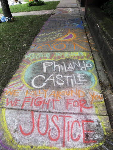 A chalk tribute to Philando Castile marks a sidewalk across the street from the governor's residence as demonstrators gather outside the governor's residence Friday, July 8, 2016, in St. Paul, Minn., where protests continue over the shooting death by police of Castile after a traffic stop Wednesday, July 6, in Falcon Heights. (AP Photo/Jim Mone)