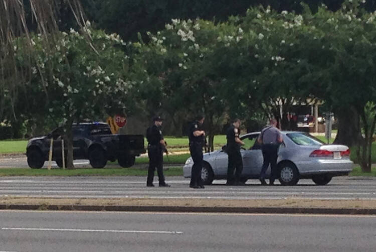 Authorities talk to the driver of a car near an area where several officers were shot while on duty less than a mile from police headquarters, Sunday, July 17, 2016, in Baton Rouge, La. (AP Photo/Mike Kunzelman)