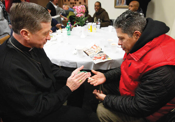 TURNING TOWARD MORNING. Archbishop Blase J. Cupich of Chicago blesses a rosary for Jaime Dones as he visited with patrons during a Thanksgiving dinner put on by Catholic Charities on Nov. 27, 2014. The dinner is held for the homeless and the hungry. 