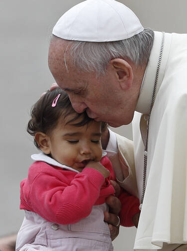 Pope Francis kisses a young girl as he leaves his general audience in St. Peter's Square at the Vatican, Oct. 29 (CNS Photo, Paul Haring).