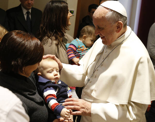 Pope Francis blesses a baby as he visits St. Thomas the Apostle Parish on the outskirts of Rome on Feb. 16