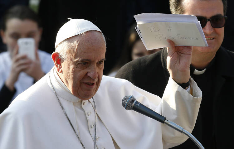 Pope Francis holds up letters he received from young people during a visit to St. Mary Mother of the Redeemer Parish on the outskirts of Rome March 8. (CNS photo/Paul Haring)