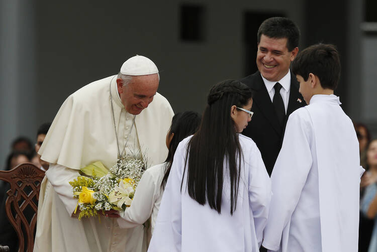Pope Francis receives flowers at Silvio Pettirossi International Airport in Asuncion, Paraguay, July 10 (CNS photo/Paul Haring).