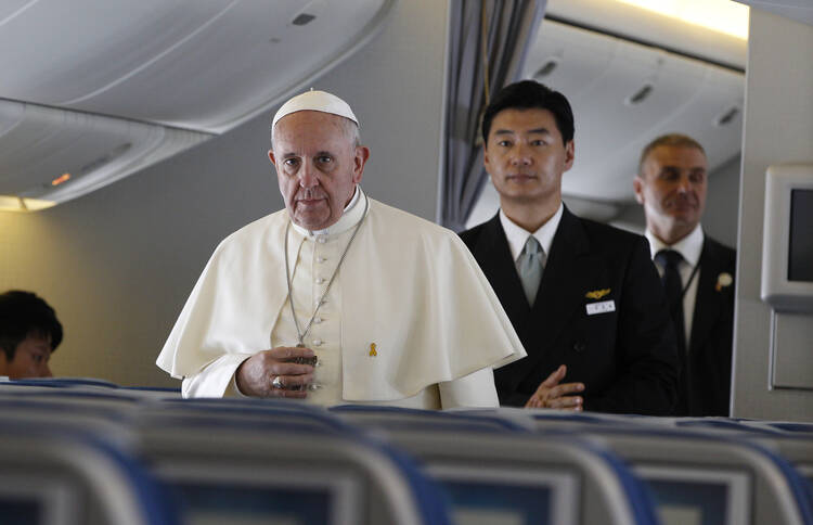 Pope Francis walks down aisle aboard flight from Seoul to Rome, August 18.