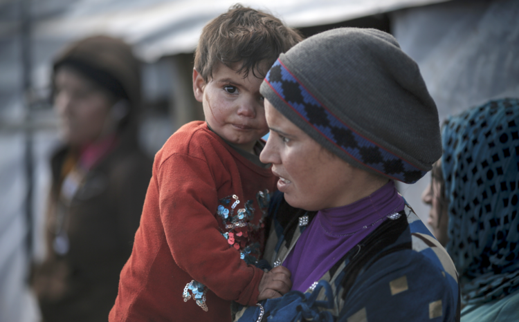 A young Syrian mother and her child in 2015 outside their tent at an informal settlement in Deir al Ahmar, in Lebanon's Bekaa Valley (CNS photo/Sam Tarling, CRS). 