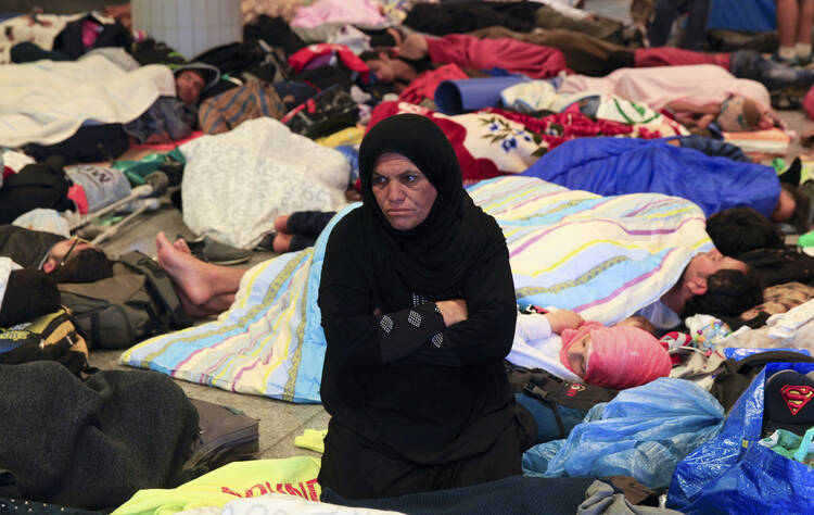 A woman sits among sleeping migrants near the Keleti railway station in Budapest, Hungary, Sept. 3 (CNS photo/Bernadett Szabo, Reuters).