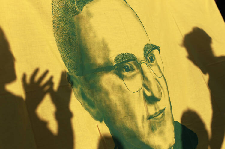 Flag with image of late Archbishop Oscar Romero seen during march prior to assassination anniversary in San Salvador
