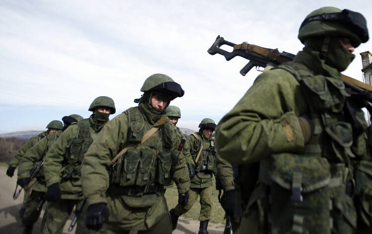 The Russians are coming? Armed men, believed to be Russian servicemen, march outside a Ukrainian military base in Crimea on March 7.