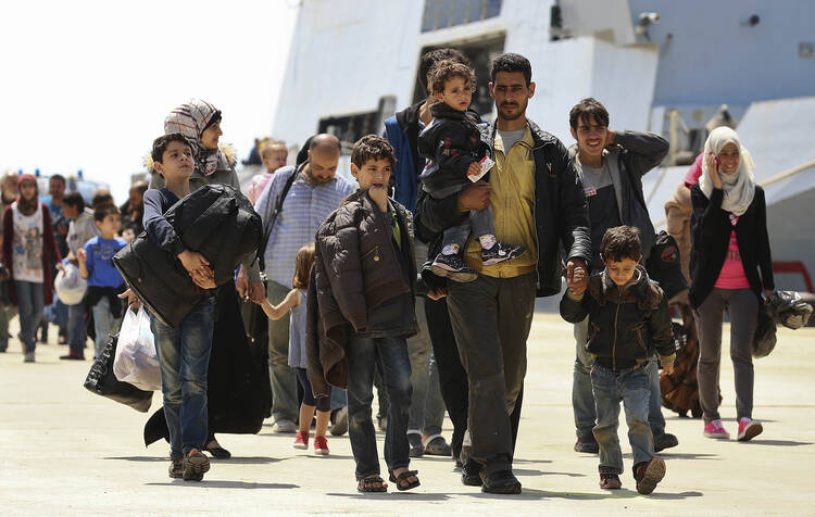 Migrants walk as they disembark from navy ship in Sicilian harbor of Augusta.