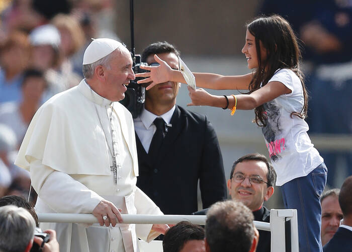 A young girl greets Pope Francis as he arrives in St. Peter's Square on Sept. 11