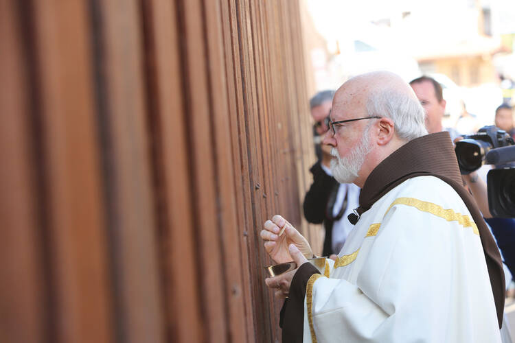 COMMUNION. Boston’s Cardinal Seán O’malley at the border fence in Nogales, Ariz.