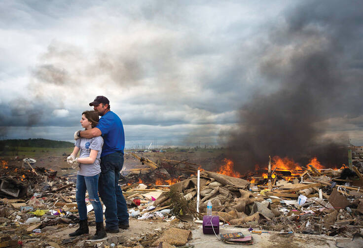 A father hugs his daughter while taking a break from helping friends sift though rubble from homes destroyed in an Arkansas tornado.