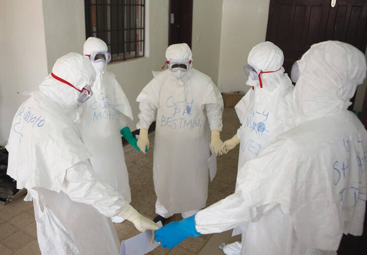 CIRCLE OF LIFE. Health workers at prayer as they start their shift in Monrovia, Liberia, in September.