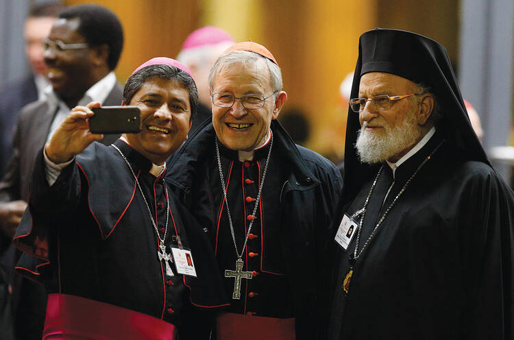 Selfie Reflection. An unidentified bishop with German Cardinal Walter Kasper and Melkite Catholic Patriarch Gregoire III Laham strike a pose after the synod’s final session on Oct. 24. 