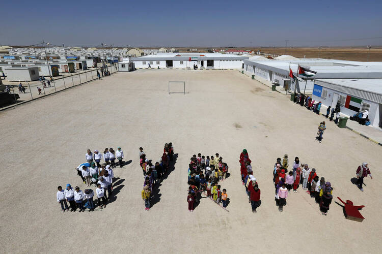 Syrian refugee children at the Mrajeeb Al Fhood refugee camp in Jordan form the word "Syria" during an event to commemorate four years of the Syrian conflict, March 15. (CNS photo/Muhammad Hamed, Reuters) 