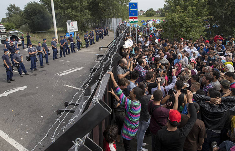 Migrants stand in front of a barrier at the border with Hungary near the village of Horgos, Serbia, on Sept. 16, 2015. (Photo courtesy of Reuters/Marko Djurica)