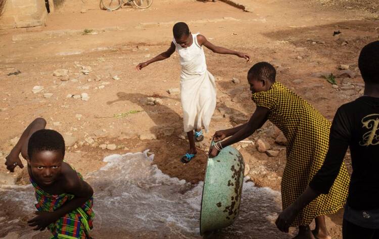 Water is thrown in the street in front of a Vivre dans l’Espérance (Living in Hope) orphanage after a bath in Togo. Photo by Julien Pebrel / Myop