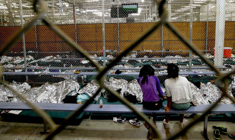 Two young girls watch a World Cup soccer match in a holding area where hundreds of mostly Central American immigrant children are being processed in Nogales, Az., on June 18.