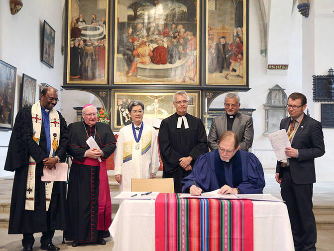 Reformed, Catholic, Lutheran and Methodist leaders look on in St. Mary's City Church in Wittenberg, Germany, as the Rev. Chris Ferguson, World Communion of Reformed Churches general secretary, signs the declaration expressing Reformed churches' support for the Catholic-Lutheran Joint Declaration on the Doctrine of Justification. Photo courtesy of WCRC/Anna Siggelkow