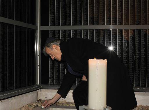 In this Dec. 10, 2009 file photo, Elie Wiesel lights a candle for Holocaust victims on a memorial wall, which identifies tens of thousands of Hungarian Holocaust victims, in the Holocaust Memorial Center in Budapest, Hungary (AP Photo/Bela Szandelszky).