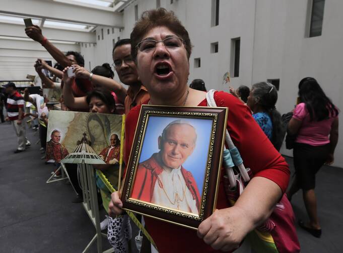 A woman holds up a portrait of St. John Paul II after a Mass at the Basilica of Guadalupe in Mexico City April 27 to celebrate the canonizations of Sts. John Paul and John XXIII. (CNS photo/Henry Romero, Reuters)
