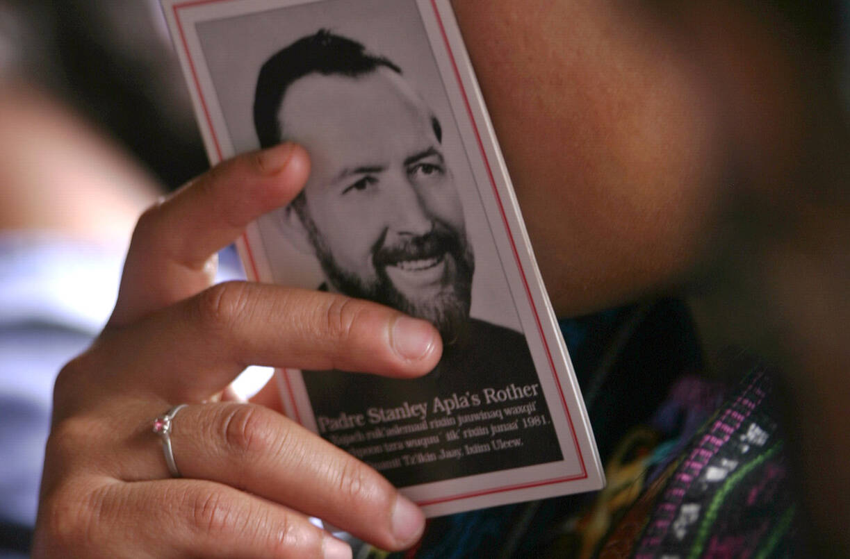 A woman holds a booklet with a picture of Father Stanley Rother