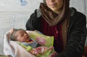 Photo: Raghad Al-Hussein, a 30-year-old Syrian refugee, holds her newborn child inside their makeshift shelter in the village of Jeb Jennine, in Lebanon on Nov. 22. CNS Photo: Paul Jeffrey.)