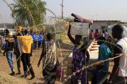 People walk past razor wire Jan. 7 at Tomping camp, where thousands of displaced people who fled their homes are sheltered by the United Nations near Juba, South Sudan. (CNS photo/James Akena, Reuters)