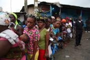 Liberian police control residents in Ebola quarantined area as they wait for food rations. (CNS photo/Ahmed Jallanzo, EPA)