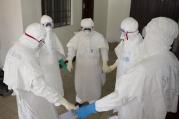 Health workers wearing protective equipment hold hands as they pray at the start of their shift before entering the Ebola treatment center in Monrovia, Liberia, Sept.30. Joe Sehnert, a member of Ascension Parish in Chesterfield, Mo., is helping the local community cope with the Ebola outbreak as a lay missionary with Liberia Mission, an effort of Franciscan Works. (CNS photo/Christopher Black, WHO, Handout via Reuters) See EBOLA-SEHNERT Oct. 8, 2014.