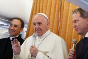 Pope Francis answers questions from journalists aboard his flight from Malmo, Sweden, to Rome Nov. 1. At left is Father Mauricio Rueda Beltz, papal trip planner; at right is Greg Burke, Vatican spokesman.(CNS photo/Paul Haring)