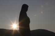 The sun sets behind a statue of Mary on Apparition Hill in Medjugorje, Bosnia-Herzegovina. (CNS photo/Paul Haring)