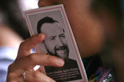 A woman holds a booklet with a picture of Father Stanley Rother