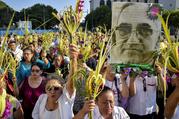 Worshippers wave palm fronds near an image of Blessed Oscar Romero during a Palm Sunday procession March 25 in San Salvador, El Salvador. Catholic officials in El Salvador were shaken and expressed outrage and sadness after the assassination of a 36-year-old priest during Holy Week, in what some suspect may be a gang killing. (CNS photo/Armando Escobar, EPA)