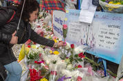 A woman places a flower at a makeshift memorial on April 25 near the Toronto sidewalk where 10 people were killed on April 23 after a van ran into them. (CNS photo/Michael Swan, The Catholic Register)