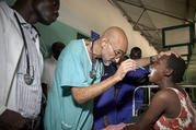 Dr. Tom Catena, a Catholic lay missionary from the United States, examines a patient during rounds in late April at the Mother of Mercy Hospital in Gidel, a village in the Nuba Mountains of Sudan. The Catholic hospital, at which Catena is often the only physician, is the only referral hospital in the war-torn area. (CNS photo/Paul Jeffrey)