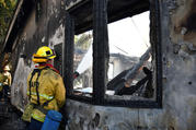 A firefighter douses water on a house after it was burned by the wind-driven Getty Fire outside Los Angeles Oct. 28, 2019. By Oct. 29, the fire had burned more than 600 acres and was 5% contained, according to the Los Angeles Fire Department. (CNS photo/Gene Blevins, Reuters) 