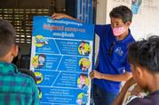 A Catholic Relief Services staff member in Cambodia explains the latest COVID-19 information to a small group of village leaders. (CNS photo/Jennifer Hardy)